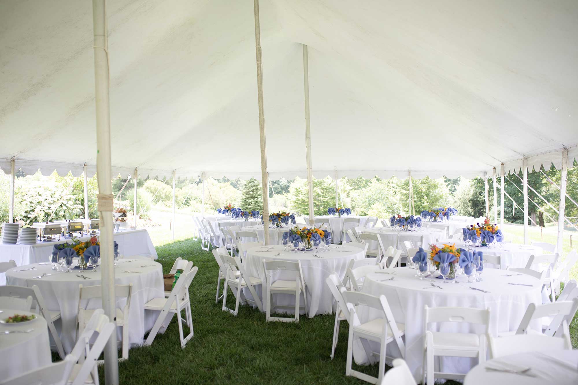 White Tablecloths and Colorful Centerpieces Outside Under a Large White Tent with folding chairs