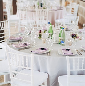 Round banquet table with white tablecloth and white Chiavari chairs